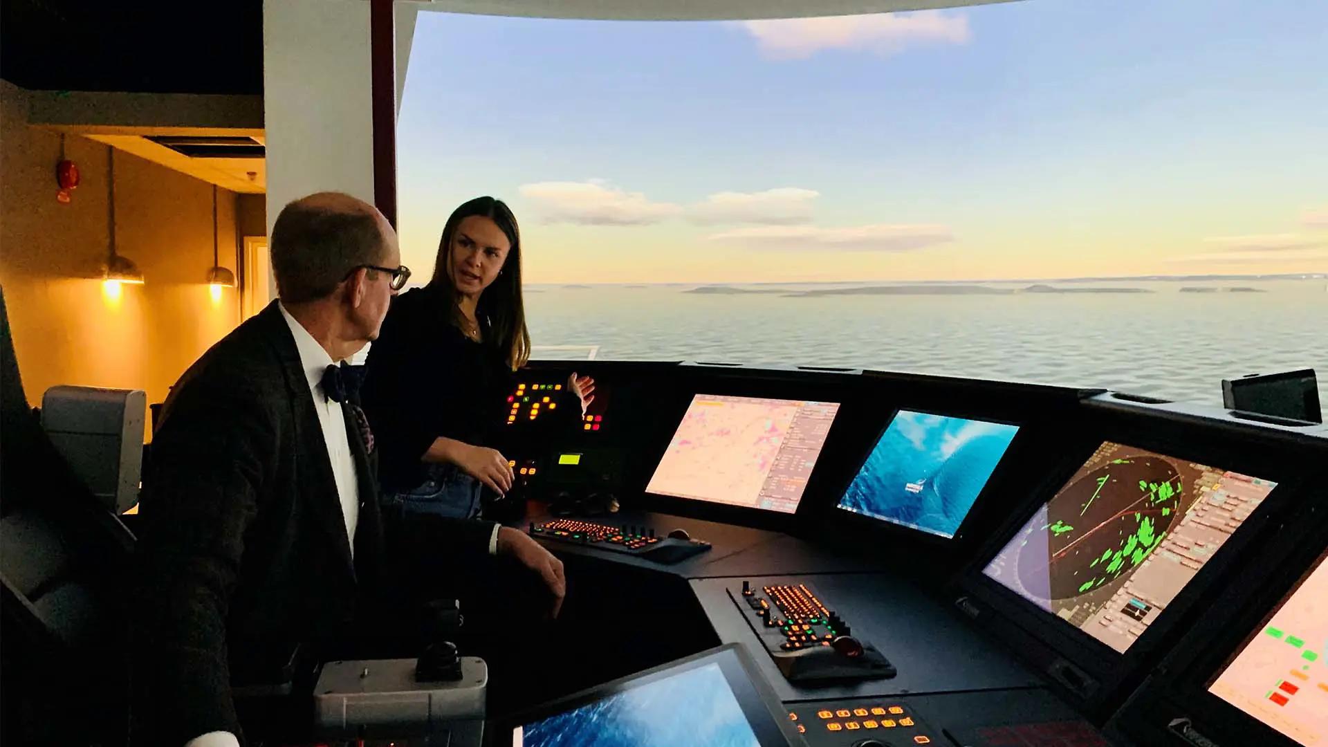 Sjökaptensstudent Hilda instruerar M-politker Ulrik Nilsson vid simulatorn. 