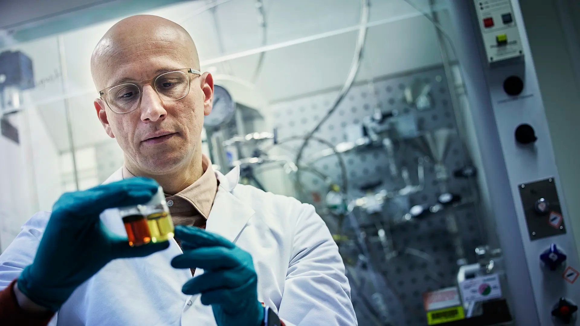 Forskare i kemisk reaktionslabb med bioolja i handen 