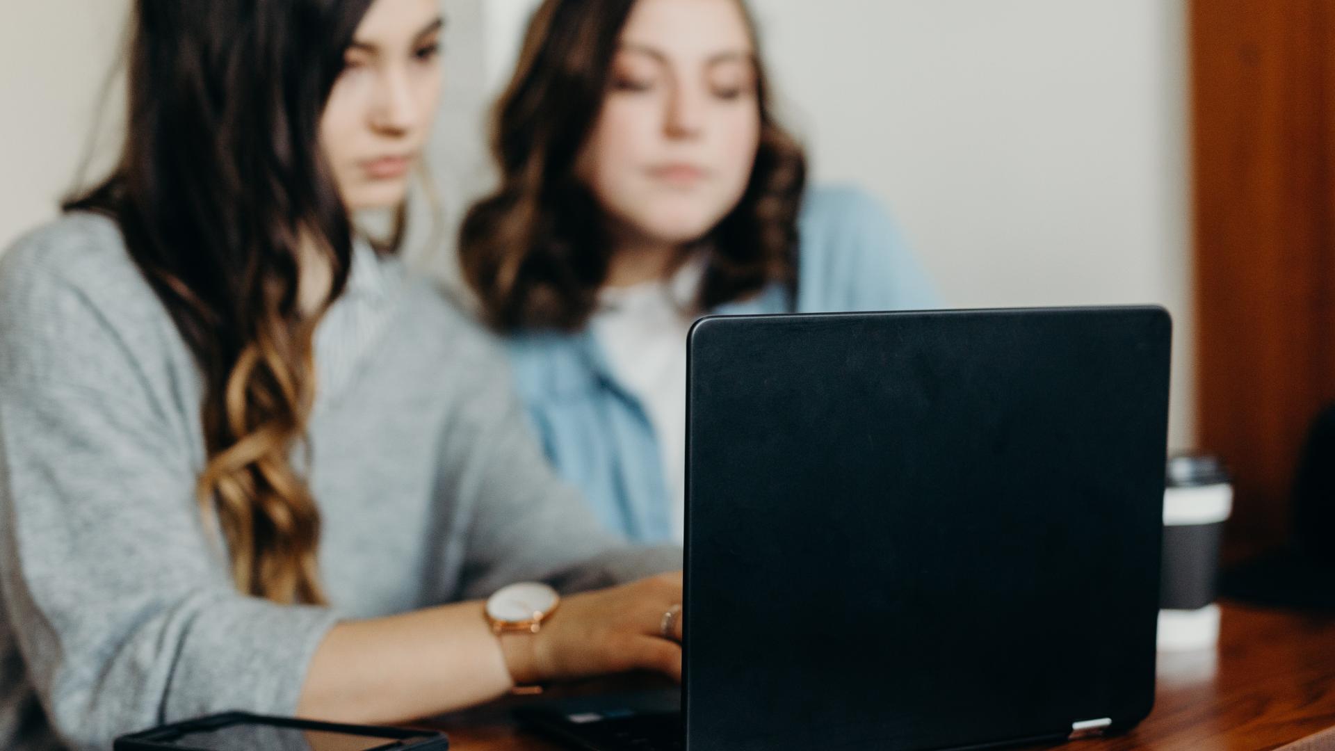 Två tjejer som tittar på en laptop