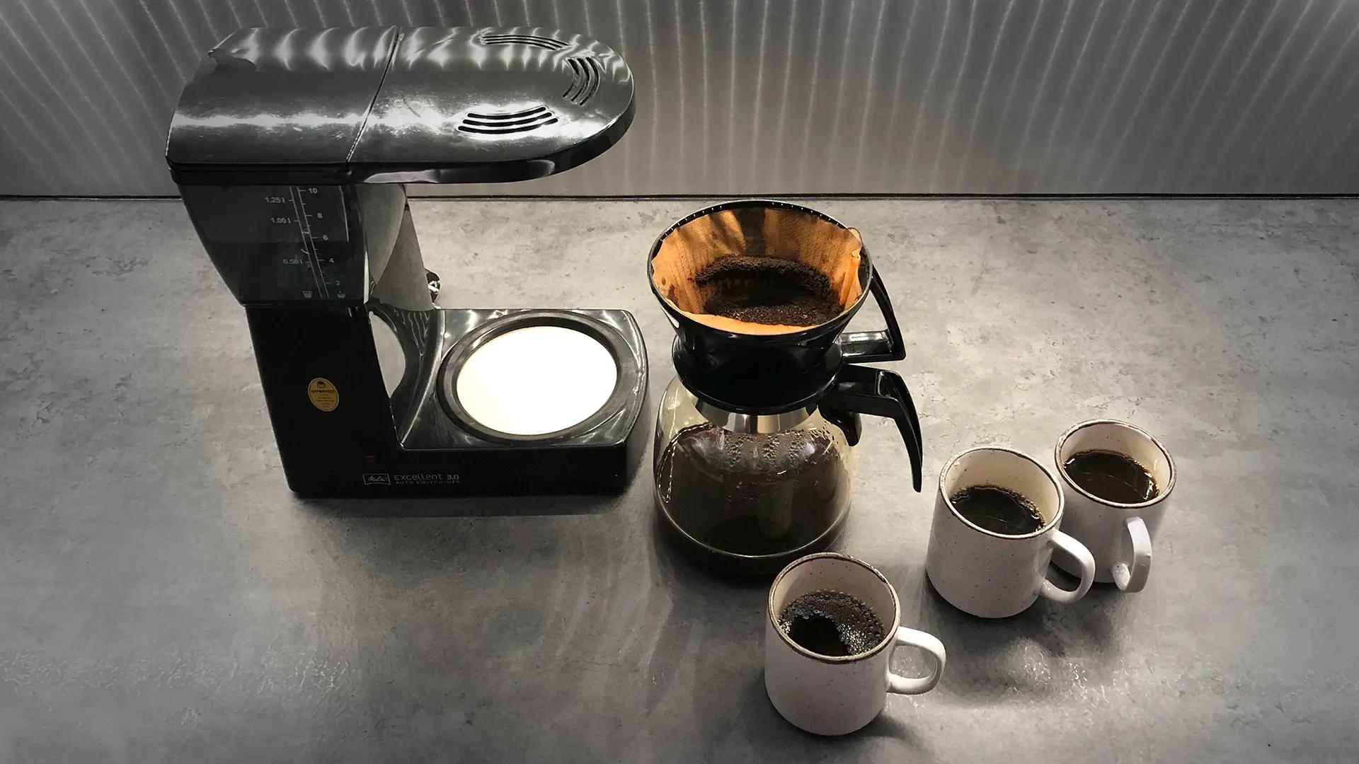 En kaffebryggare och tre kaffekoppar. 