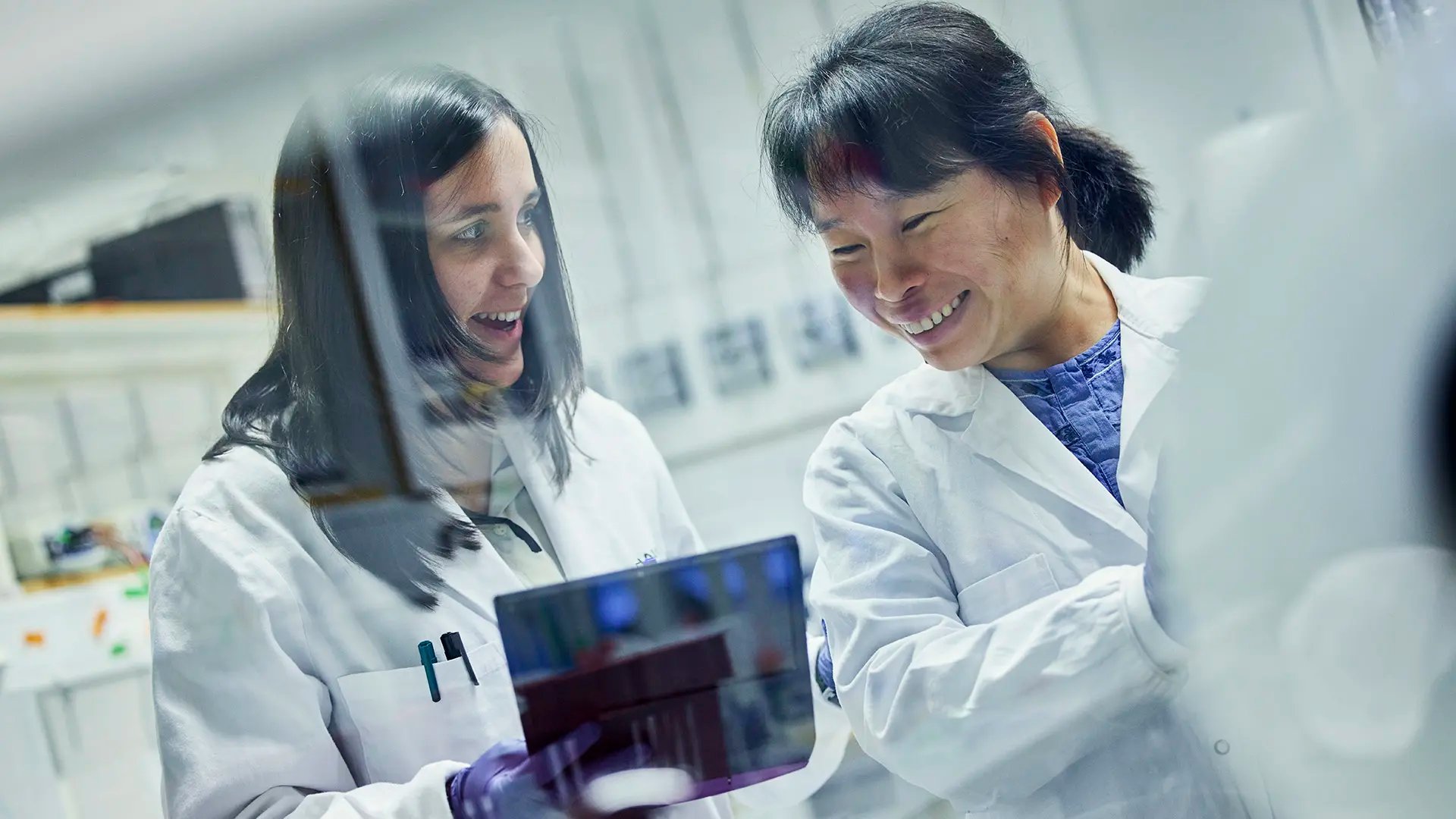 Two happy researchers in white lab coats handling laboratory equipment