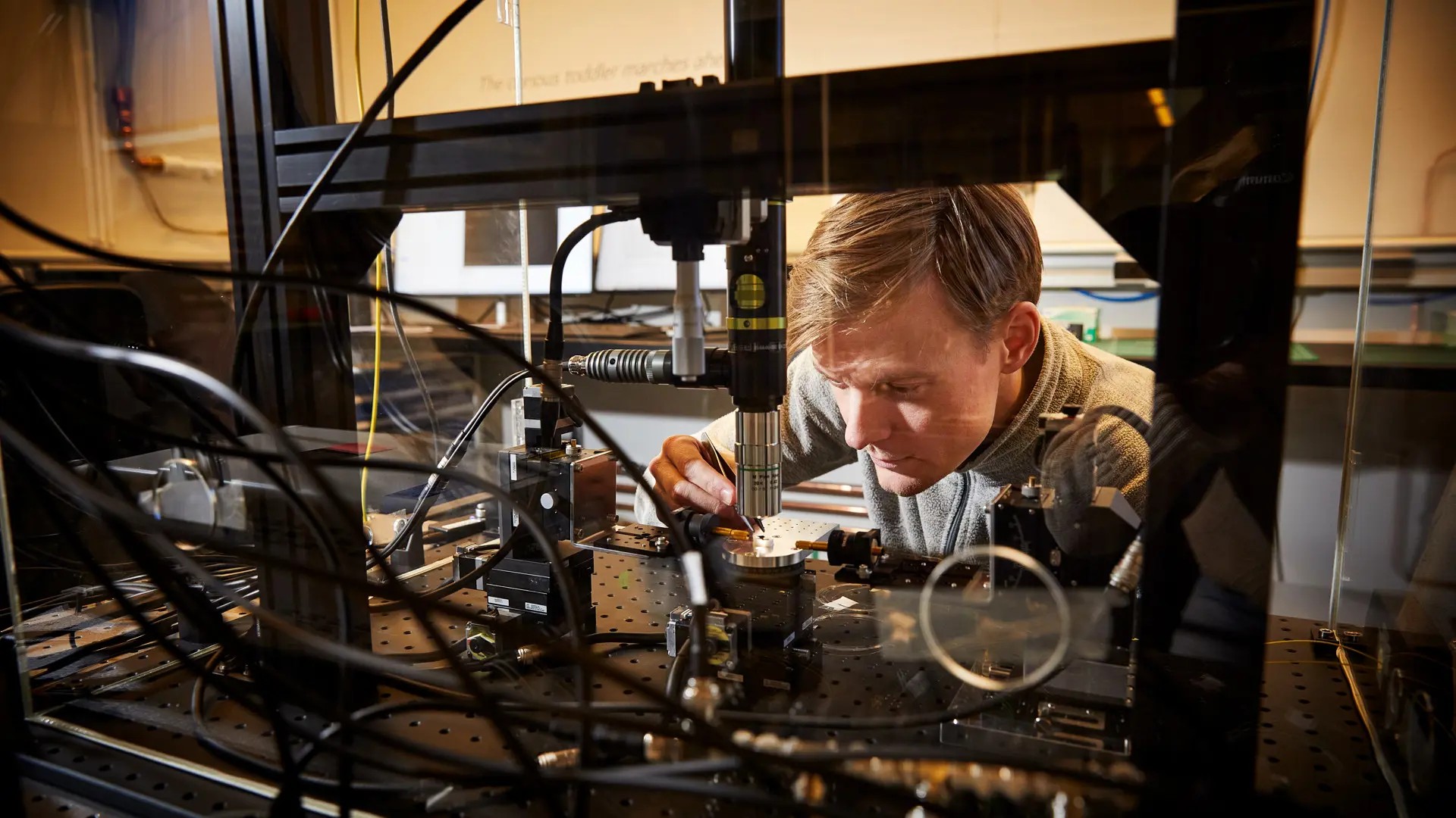 Doktorand Johan Kolvik placerar ett chip med optomekaniska kristaller under mikroskopet i kvantfotoniklabbet. Foto: Anna-Lena Lundqvist